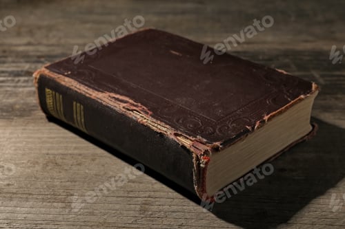 Preview: One old hardcover book on wooden table, closeup