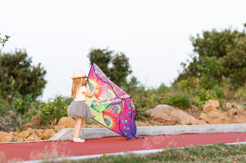 Preview: Happy Caucasian little girl with blonde hair playing with kite outdoor at hot summer day