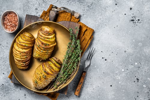 Preview: Baked Hasselback Potato with Fresh thyme and rosemary. Gray background. Top view. Copy space