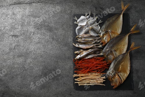 Preview: Many different dried fish snacks on grey table, top view. Space for text