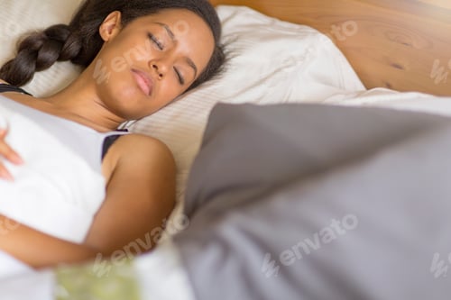 Preview: High angle view of young woman lying on back in bed eyes closed sleeping