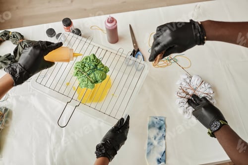 Preview: Gloved hands of young African American man and woman tie dying clothes