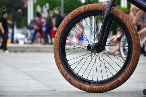 Preview: A BMX bike wheel against the backdrop of a blurred street with cycling riders