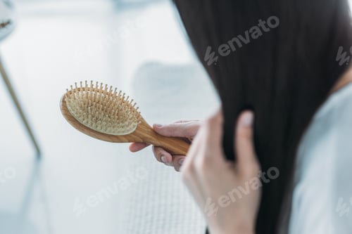 Preview: cropped shot of young brunette woman holding hairbrush, hair loss concept