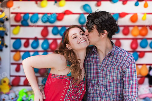 Preview: Romantic couple kissing on cheek at fairground stall