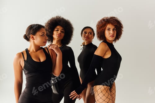 Preview: four appealing african american women in black alluring attire posing together, fashion concept