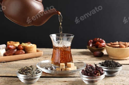Preview: Pouring freshly brewed Turkish tea into glass at wooden table, closeup