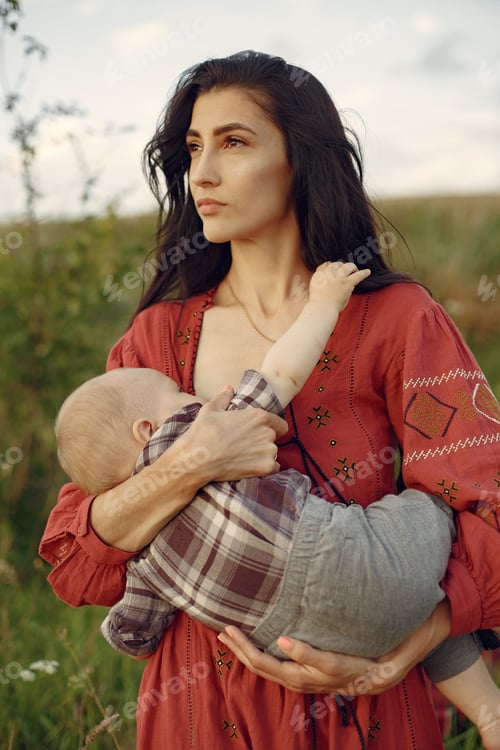 Preview: Woman sitting on a blanket and breastfeeding her little son