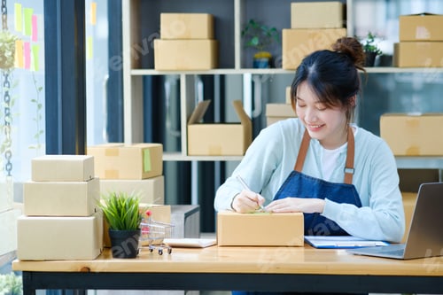 Preview: Online small business owner writing address on parcel box.