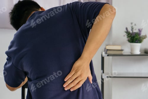 Preview: Closeup of man suffering from pain back while sitting on chair at office,body-muscles problem.
