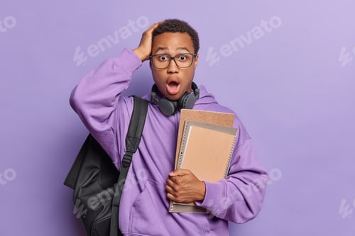 Preview: Horizontal shot of scared emotive African guy with short curly hair and beard carries black rucksack