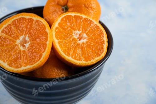 Preview: Close up photo of black bowl full with whole or half cut mandarins