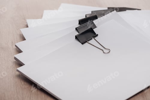 Preview: stacks of blank paper with metal binder clips and copy space on wooden desk