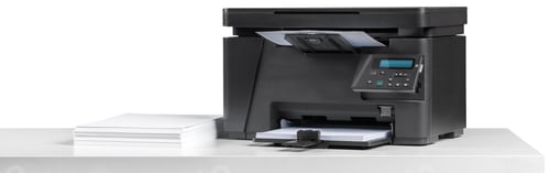 Preview: Printer on a table with stacked paper ready for printing documents at an office space