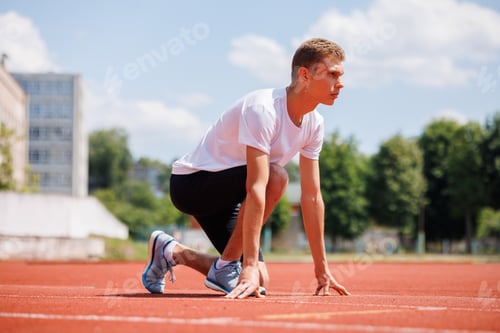 Preview: Young male athlete in starting position on running track