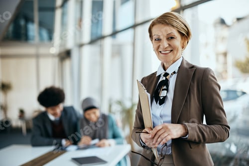 Preview: Happy senior financial advisor working at her office and looking at camera.