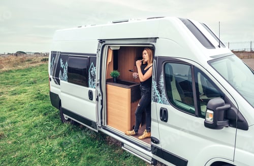 Preview: Woman brushing teeth in the morning at the door of her campervan