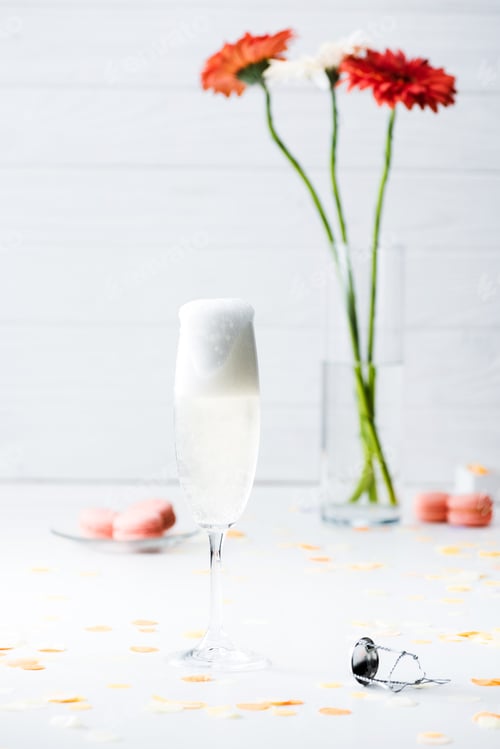 Preview: selective focus of glass full of champagne and macarons on grey background