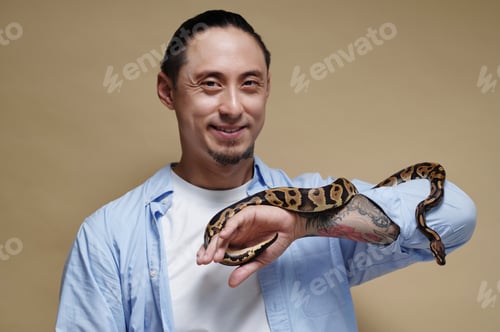 Preview: Portrait of Smiling Man Holding Python Snake on Arm