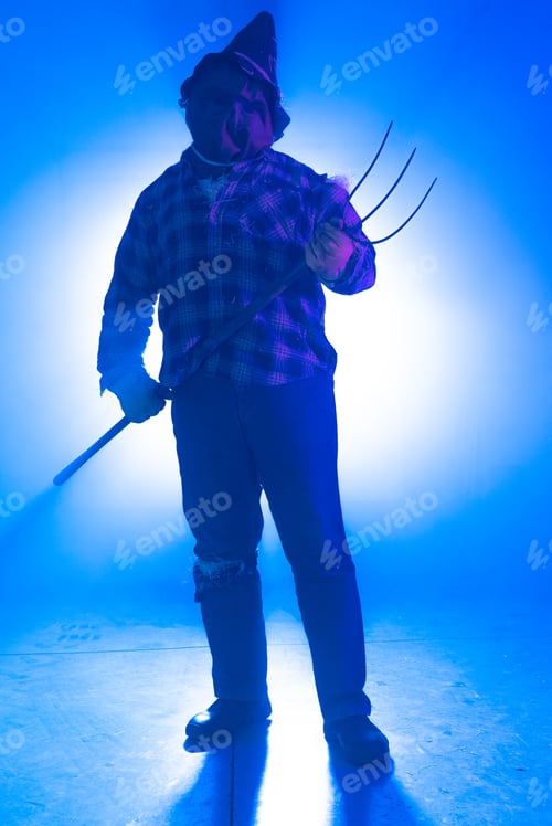 Preview: Vertical shot of a person in a scary scarecrow costume in a blue room