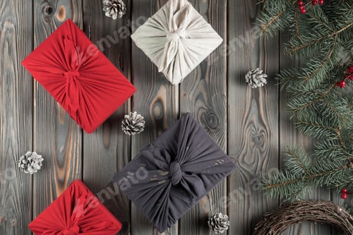 Preview: Christmas presents composition in furoshiki package, top view. Spruce branches, cones and gift boxes