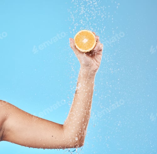 Preview: Hand, orange and water with a woman in studio on a blue background for health or hydration. Food, l