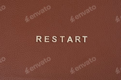 Preview: Word restart with abstract wooden letters. Background brown leather
