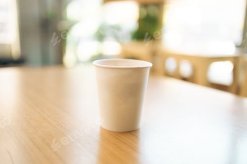 Preview: Paper coffee cup on a wood table in coffee shop.
