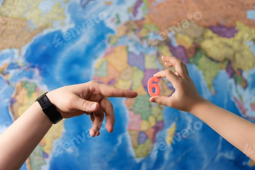 Preview: Adult And Child Hands Holding Numbers Plastic Toy On The World Political Map Background. Travel
