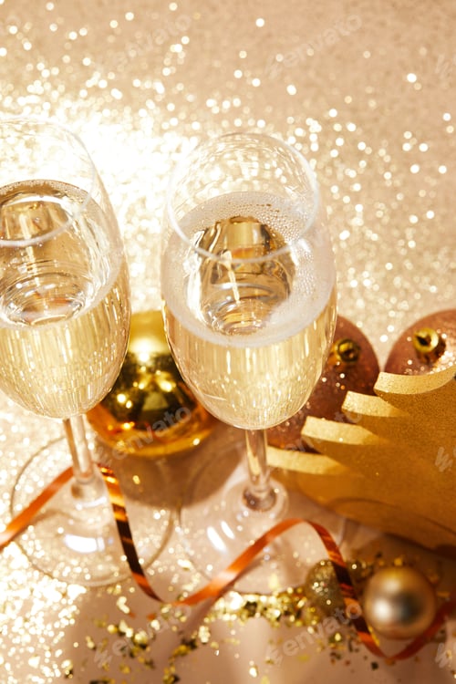 Preview: high angle view of christmas balls and two glasses of champagne with glitter on tabletop