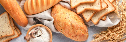 Preview: Various crispy breads and buns, wheat flour and ears on light gray concrete background table. Top vi