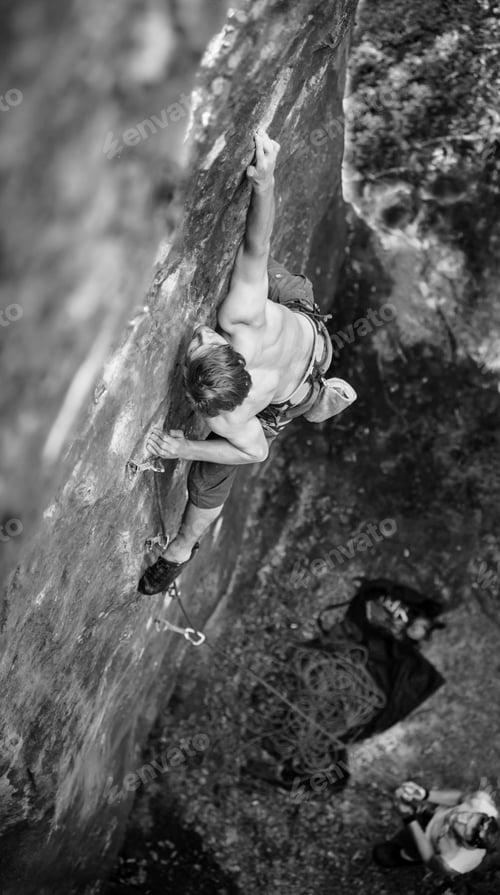 Preview: Muscular rock climber climbs on cliff wall with rope