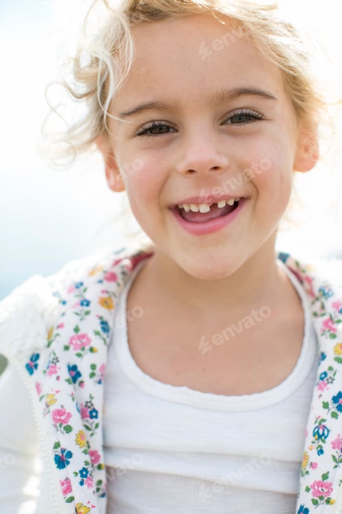 Preview: Portrait of cute blond girl with tooth missing at coast