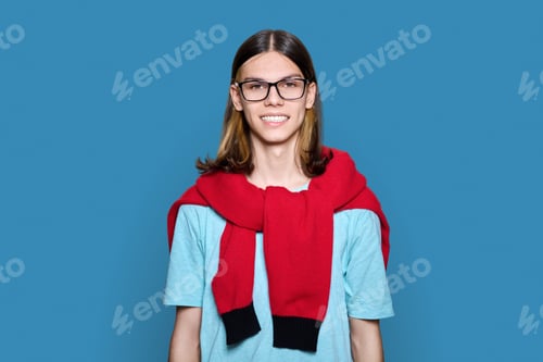 Preview: Headshot portrait of teenage guy looking at camera on blue background