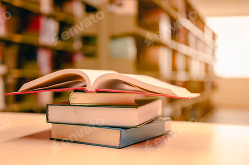 Preview: Opened book with stack of books on the desk wood in the library. Education background concept.