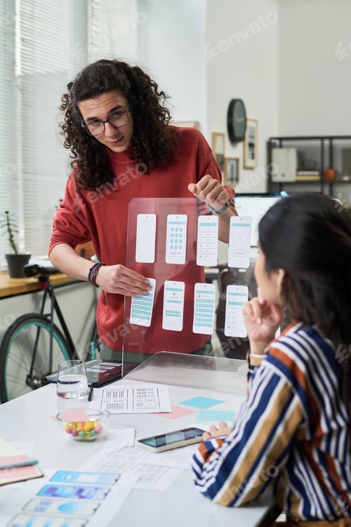 Preview: Young Adult Caucasian Man Explaining Mobile App Interface Design to Colleague
