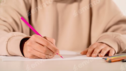 Preview: Cropped view of woman drawing with pink pencil on paper