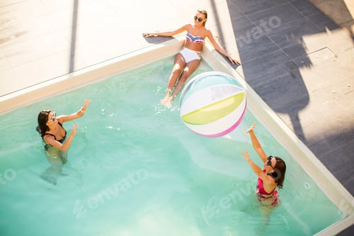 Preview: Pretty young women playing with ball in swimming pool