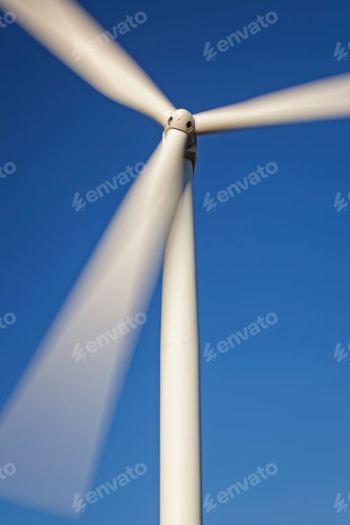Preview: Close-up of a wind turbine with spinning blades against a clear blue sky, clean renewable energy.