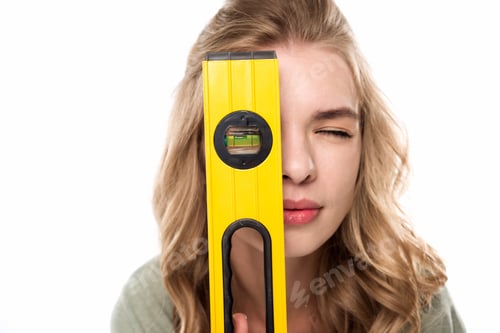 Preview: Young blonde woman looking through level tool, renovation concept