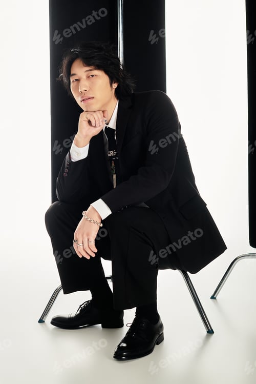 Preview: Young Asian man showcases modern fashion style with chic pose in a minimalist setting