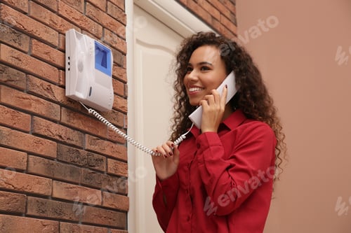 Preview: Young African-American woman answering intercom call indoors