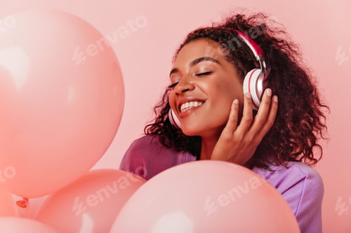 Preview: Close-up portrait of pleasant african girl in headphones enjoying party. Glad black woman listening