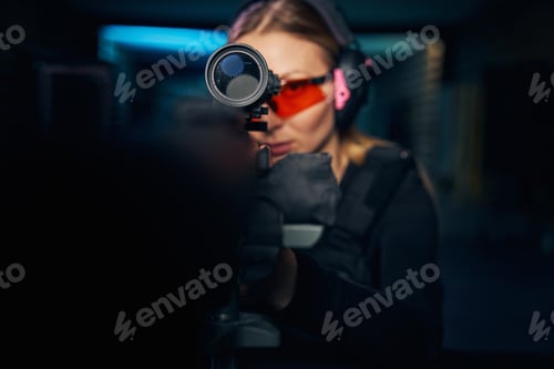 Preview: Focused young woman shooting a modern firearm