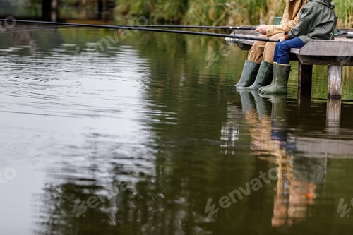 Preview: cropped view of father and son fishing together with rods on wooden pier at lake