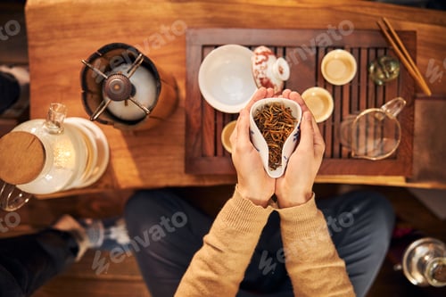 Preview: Young woman holding bowl of dried tea leaves