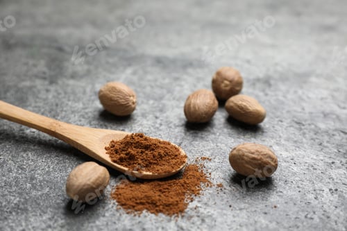Preview: Spoon of nutmeg powder and seeds on grey table
