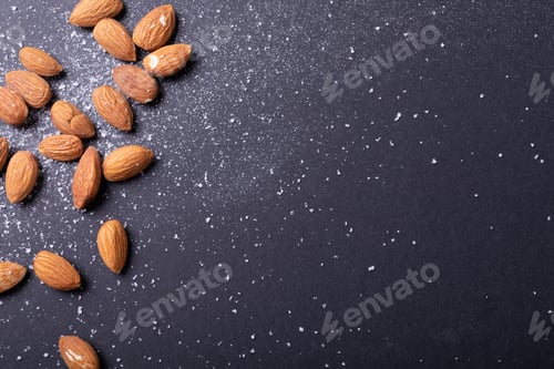 Preview: Overhead view of almonds with salt on black background