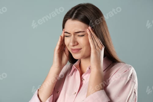 Preview: Young woman suffering from migraine on grey background