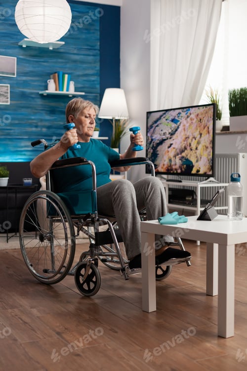 Preview: Handicapped senior woman in wheelchair stretching arms muscles exercising body resistance